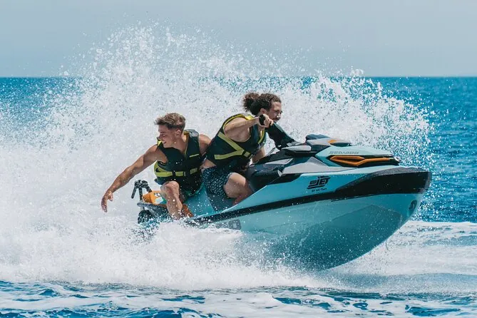 Two riders in life jackets on a jet ski with spray flying in Langkawi